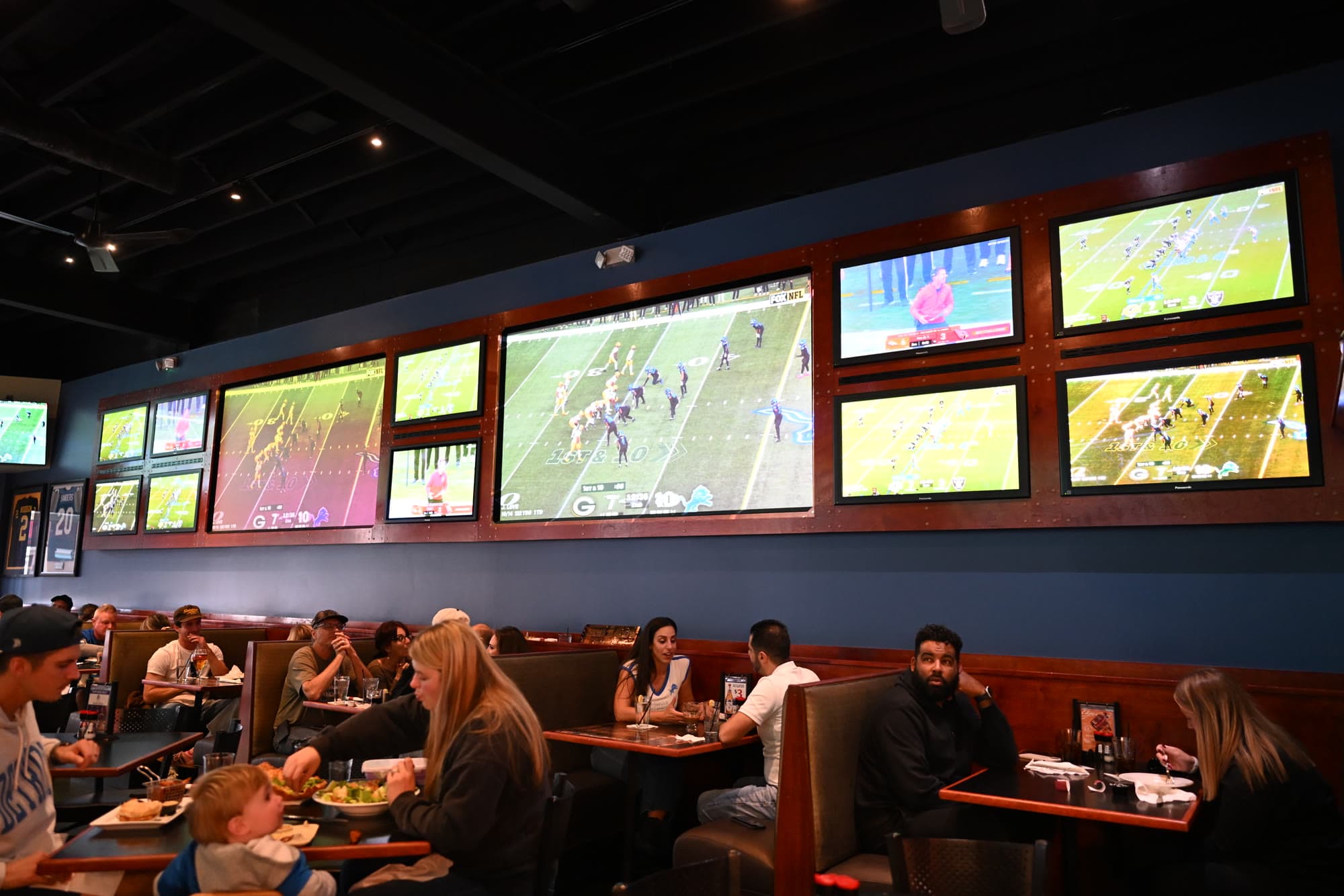 Guests in booths under a wall of TVs