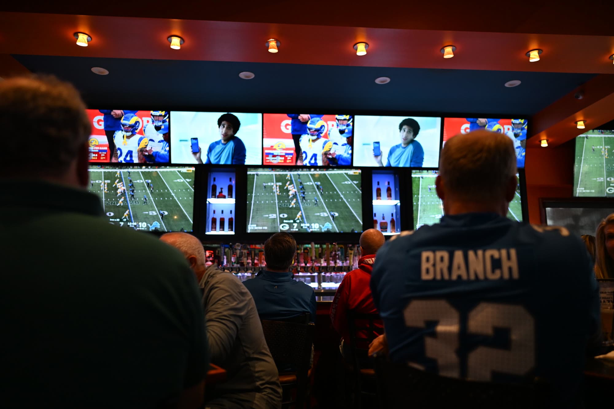 Lions fans in jerseys watching the TV wall